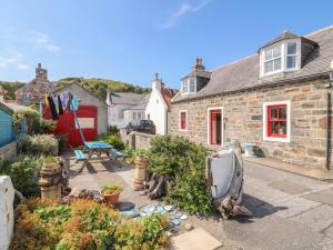 a stone house with a garden in front of it at Dookers' Hoose in Buckie