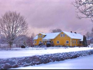 a large yellow house with snow on the ground at Vitahästen in Hästveda