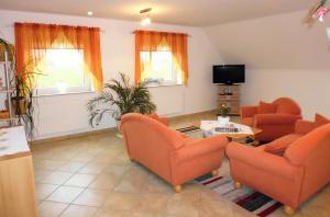 sala de estar con sillas de color naranja y TV en Ella's Ferienwohnung, en Roikier