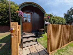 a small house with a wooden door and a fence at The Beeches in Scarisbrick