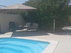 a swimming pool with a table and an umbrella at Studio cosy in Sorgues