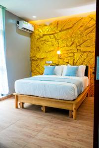 a bedroom with a large bed with a yellow stone wall at The Mimshach in Asese