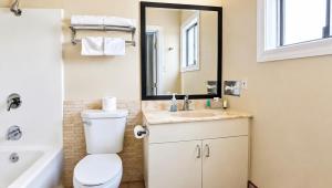 a bathroom with a toilet and a sink and a mirror at Magnuson Hotel Blythe in Blythe +36 photos