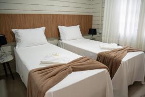 two beds in a hotel room with towels on them at Sítio Monte Frederico in Nova Trento