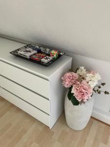 a white dresser with a vase of flowers next to a drawer at The White Farm in Skanderborg +12 photos