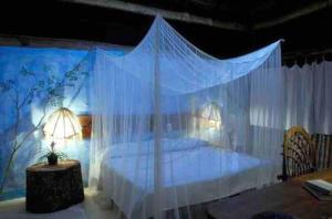 a bedroom with a bed with a mosquito net at Hotel Puerta Calakmul in Conhuas