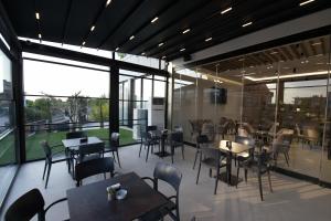 a restaurant with tables and chairs and large windows at Hotel New City Tirana in Kamëz