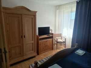 a bedroom with a bed and a tv and a cabinet at Haus der Sonne Apartment in Blaufelden
