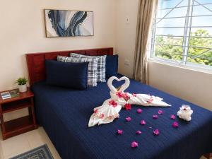 a bedroom with a bed with two swans made out of flowers at AG3K Oasis in Buccoo