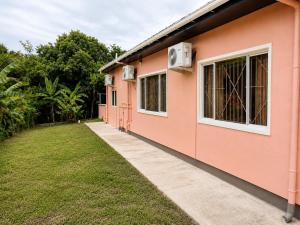 a pink house with a lawn next to it at AG3K Oasis in Buccoo