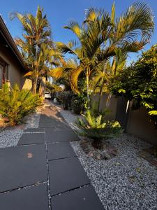 a garden with palm trees and a walkway at BoniM Guesthouse - aka Magisha Guesthouse in Nelspruit