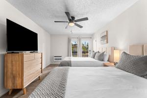 a bedroom with two beds and a flat screen tv at Suites at Waterside in Branson