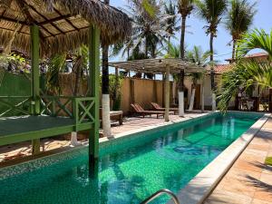a swimming pool next to a resort with palm trees at Wind & Sun Kite Pousada in Canoa Quebrada