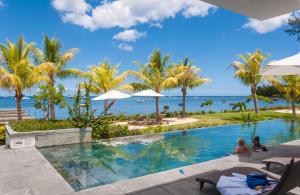 a pool at a resort with palm trees and the ocean at Latitude - with private plunge pool in Rivière Noire