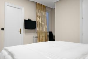 a bedroom with a white bed and a television at Santacruz in Oviedo