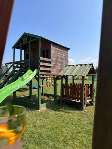 a playground with a wooden house and a slide at Domki Marylkowo in Rusinowo