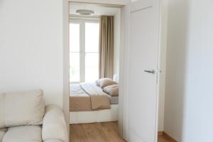 a mirror in a bedroom with a bed and a window at Erdvūs apartamentai Prie Jūros in Melnragė