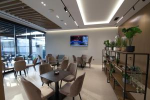 a dining room with tables and chairs and windows at Hotel New City Tirana in Kamëz