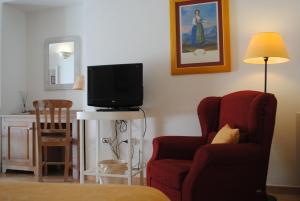 ein Wohnzimmer mit einem TV und einem Stuhl in der Unterkunft Hotel Giardino Giamperduto in Bernalda