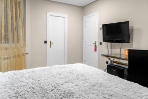a bedroom with a white bed and a flat screen tv at Santacruz in Oviedo +19 photos