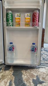 an open refrigerator with drinks and cans of soda at NEW ASSER HOTEL PYRAMID in Cairo