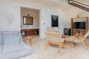 a living room with a couch and chairs and a tv at Nalhá Hotel Boutique y Villas Bacalar in Bacalar