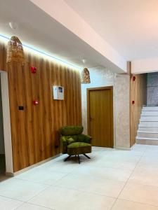 a green chair in a room with a wooden wall at Boutique Hotel Pui de Urs Fundata in Ciocanu