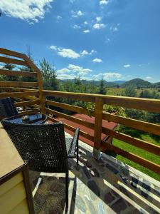 a deck with two chairs and a table and a fence at Boutique Hotel Pui de Urs Fundata in Ciocanu