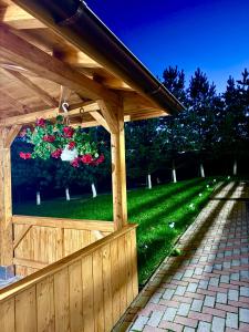 a wooden gazebo with a fence and flowers at Boutique Hotel Pui de Urs Fundata in Ciocanu