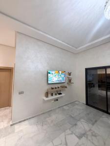 a living room with a tv on a white wall at Ocean park , for married couples and families only ,للعائلات و المتزوجين فقط Luxury fully furnished one bedroom flat next to zenata beach with five avialable swimming pool at the compound in Casablanca