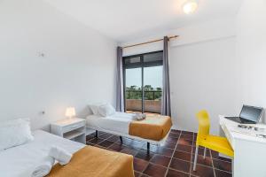 a room with two beds and a desk with a laptop at HI Almada - Pousada de Juventude in Almada