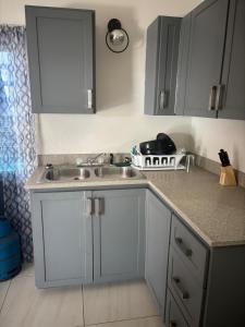 a kitchen with white cabinets and a sink at Caroline suite in Cliftons +2 photos