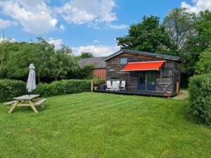 a log cabin with a red awning in a yard at Boerderijcamping KiekeBoe in Maria-Hoop