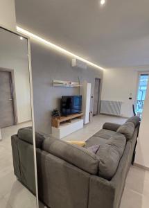 a living room with a brown couch and a television at Giulietta Apartment Cuneo in Cuneo