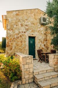 a stone building with a green door and a table at oleabungalows in Akrotiri