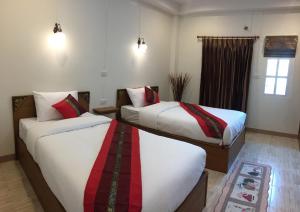 a hotel room with two beds and a window at Maesot Siri in Mae Sot