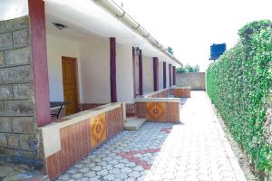 a building with a walkway next to a hedge at Lee Njiru Resort in Nakuru