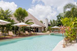 a pool at a resort with chairs and umbrellas at Nalhá Hotel Boutique y Villas Bacalar in Bacalar