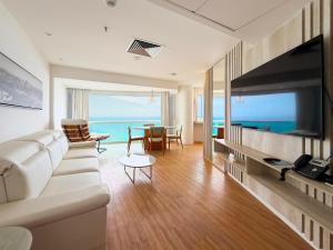 a living room with a white couch and a flat screen tv at Wyndham Rio Barra - Oficial in Rio de Janeiro