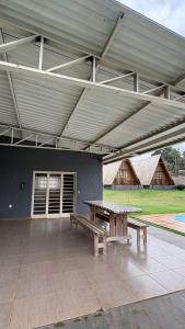 a pavilion with a picnic table and benches in front of a building at Chácara Três Chalés in Foz do Iguaçu