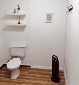 a white bathroom with a toilet and a black trash can at Depto Güemes in Río Gallegos +16 photos