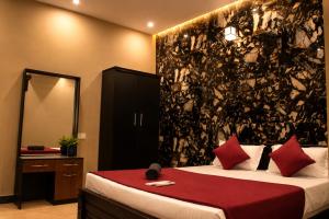 a bedroom with a bed with red pillows and a mirror at Aquora Pool Stays in Pondicherry +4 photos