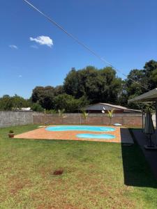 a swimming pool in a yard with trees in the background at Chácara Três Chalés in Foz do Iguaçu