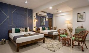 a hotel room with two beds and a table and chairs at The Velvet Anchor in Baga +3 photos