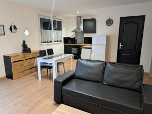 a living room with a couch and a table and a kitchen at le studio d isa in Lens