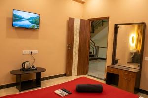 a room with a television on the wall and a red rug at Aquora Pool Stays in Pondicherry