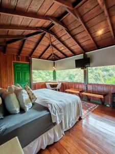 a bedroom with a bed in a room with wooden floors at Trogon Lodge in San Gerardo de Dota