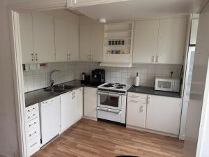 a kitchen with white cabinets and a stove top oven at Apartment in Skellefteå