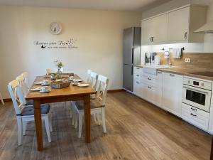 a kitchen with a wooden table and white cabinets at Spreewaldhof am Wasser in Raddusch