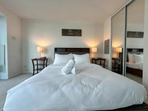 a bedroom with a large white bed with two pillows at Victoria Suites - Downtown in Toronto